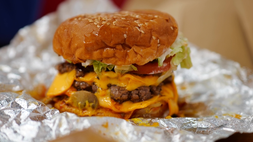 Massive stacked cheese burger sat on foil wrapper