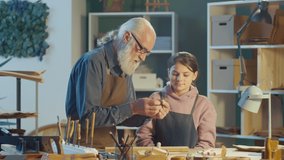 Grandfather Carpenter with his Teenage Granddaughter Works in the Workshop, Making Artistic Woodcarving. Communication of Generations. Handicraft, Skills Training. Profession, Art and Hobby Concept. - Powered by Shutterstock - Get 15% off with code: PIKWIZARD15