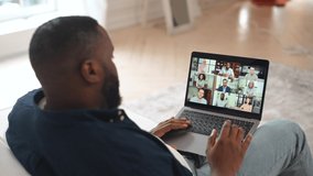 Back view on the laptop screen with a many diverse people on it, african guy using computer app for communication with employees, greeting coworkers, video conference concept