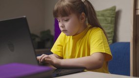 a child girl does her homework on a laptop, online distance learning on computer, schoolgirl does her homework, little kid wants to get a school education, play game on Internet, chat with classmates