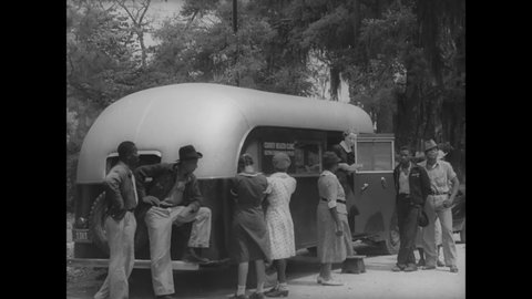 CIRCA 1939 - African-American patients line up outside a mobile health clinic in Darien, Georgia.