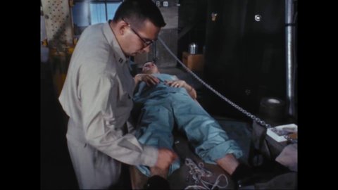 CIRCA 1963 - A USAF medic checks an airman who's about to do a drop test, and puts sensory pads on his body.