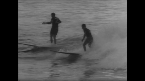 CIRCA 1966 - Men go surfing in Hawaii.