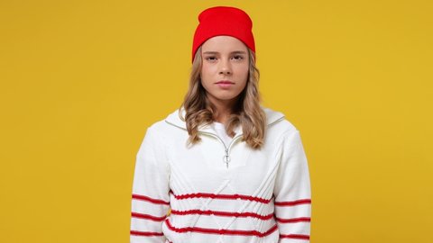 Displeased irritated sad angry distempered young girl teen student wears striped white shirt hat closed eyes cover ears do not want to listen scream isolated on plain yellow background studio portrait