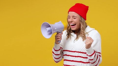Surprised promoter young girl teen student in striped white shirt hat point index finger aside scream in megaphone announces discounts sale Hurry up isolated on plain yellow background studio portrait