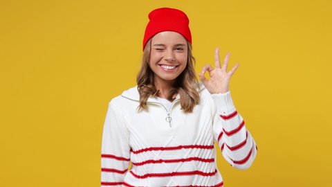 Beautiful cheery happy young girl teen student wears striped white shirt hat showing okay ok zero fingers gesture isolated on plain yellow background studio portrait. People emotions lifestyle concept