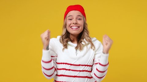 Excited jubilant overjoyed happy bright young girl teen student wears striped white shirt hat doing winner gesture celebrate clenching fists say yes isolated on plain yellow background studio portrait