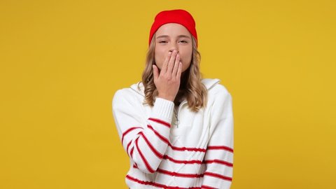 Beautiful cheery coquette happy young girl teen student wears striped white shirt hat blowing sending air kiss isolated on plain yellow background studio portrait. People emotions lifestyle concept