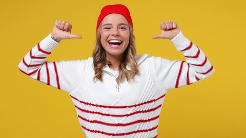 Confident happy blithesome young girl teen student wears striped white shirt hat pointing fingers on herself blinking showing thumb up like gesture isolated on plain yellow background studio portrait
