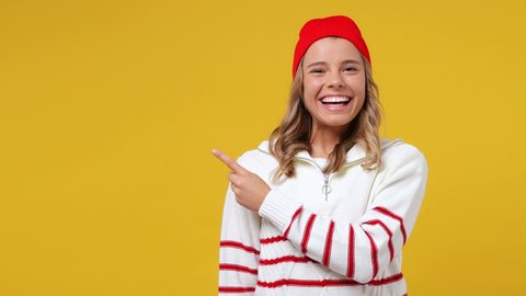 Excited promoter young girl teen student wears striped white shirt hat point finger hands aside on workspace copy space mockup promo commercial area isolated on plain yellow background studio portrait