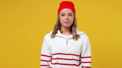 Smiling charming blithesome young girl teen student wears striped white shirt hat looking camera wink eye blink isolated on plain yellow background studio portrait. People emotions lifestyle concept