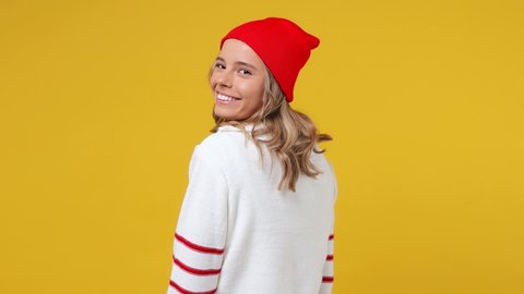 Back rear view cheerful fun happy blithesome young girl teen student wears striped white shirt hat turn around camera showing thumbs up like gesture isolated on plain yellow background studio portrait