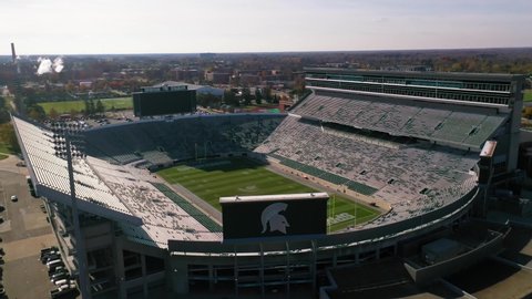EAST LANSING, MICHIGAN - CIRCA 2020s - Aerial over Spartan football stadium on the Michigan State University campus in East Lansing, Michigan.