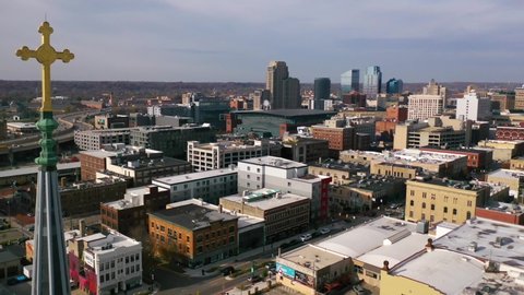 GRAND RAPIDS, MICHIGAN - CIRCA 2020s - High establish aerial of a cross on a church with the skyline of Grand Rapids, Michigan.