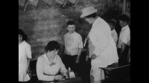 CIRCA 1919 - A school nurse checks children one by one in a schoolhouse.
