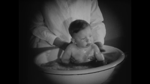 CIRCA 1919 - A nurse teaches girls how to bathe a baby.