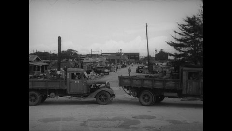 CIRCA 1945 - Japanese civilians and soldiers navigate an intersection in a war-torn city with trucks, bicycles, horses and on foot.