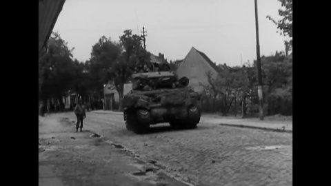 CIRCA 1945 - German civilians wave white flags and cheer for American soldiers as they drive through Zerbst in M-4 tanks.