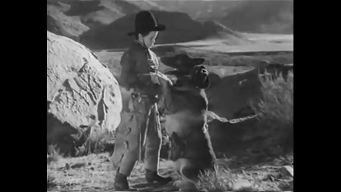 CIRCA 1937 - In this western film, a boy pretends that he's sheriff and his dog is a bandit, and the dog plays dead when he shoots it.