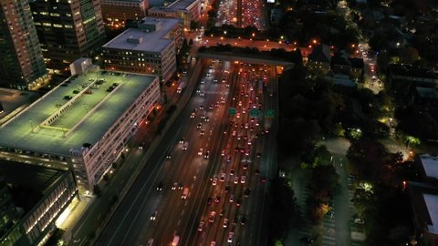 ATLANTA, GEORGIA - CIRCA 2020s - Tilting aerial shot of Atlanta, Georgia freeway and downtown skyline at dusk, sunset or night.