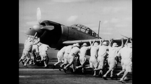CIRCA 1940s - Japanese Naval pilots move an airplane into place on the flight deck of an aircraft carrier.
