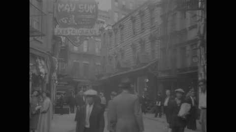 CIRCA 1937 - Pedestrians pass restaurants and go window shopping in New York's Chinatown.