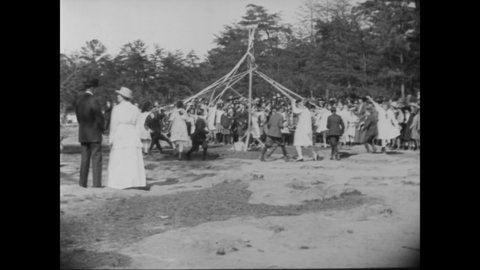 CIRCA 1919 - Children enjoy a maypole, dancing, and other activities at a field day.
