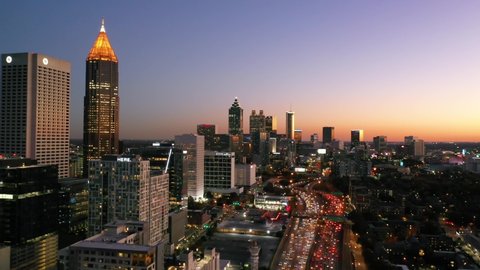 ATLANTA, GEORGIA - CIRCA 2020s - Panning aerial shot of Atlanta, Georgia freeway and downtown skyline at dusk, sunset or night.