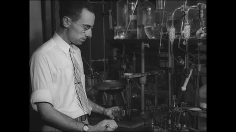 CIRCA 1946 - A chemist hands a tube of plutonium to General Groves, overseer of the Manhattan Project.