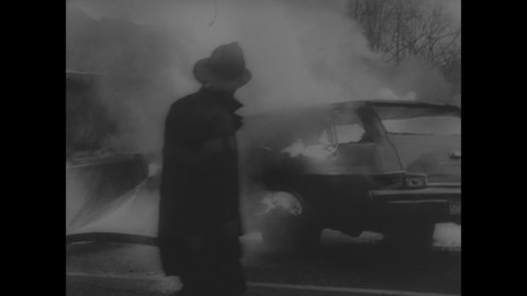 CIRCA 1966 - Firemen work to put out the blaze after a disastrous car-truck collision.