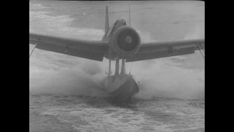 CIRCA 1942 - A US Navy seaplane is hoisted onto a ship so mechanics can inspect it.