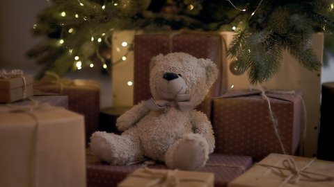 Gifts Under Christmas Tree. Many Boxes And Bear Toy. Branches Of Christmas Trees With Garlands Over Boxes. New Years Holiday.