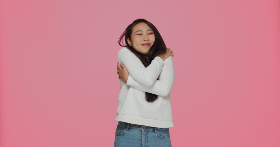 Happy woman hugging herself feeling self love and care on pink background. Body positive, acceptance, good self esteem Royalty-Free Stock Footage #1083648724