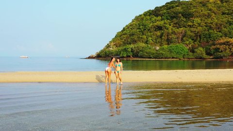 Young women washing their feet on crystal clear water of shallow lagoon on exotic beach of tropical island in Ko Pha Ngan, Thailand