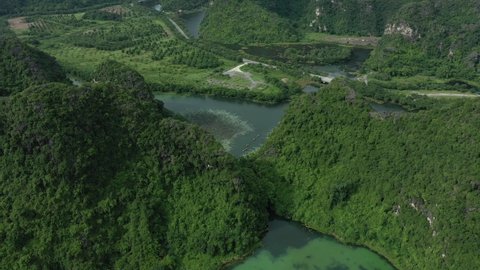 aerial drone shot of tourist boats with travellers floating along the mountain river in Ninh Binh National Park, Vietnam. Panoramic view, landscape, forest, green paradise.