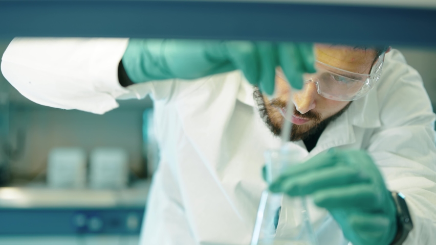 Medical research Laboratory. Portrait of a male scientist stirring a liquid for analysis. An advanced scientific laboratory for the development of medicines and biotechnologies. Close-up.
