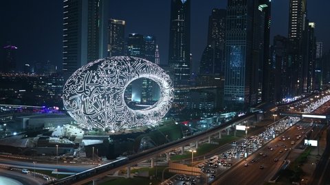 Museum of the future with lights on at night. Medium shot. Skyline and highway traffic.
Dubai, UAE - October, 2021