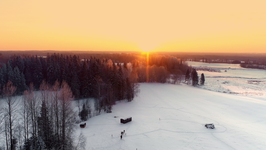 Aerial view showing family walking on snowy winter path in forest during golden sunset at horizon | Shutterstock HD Video #1083668641