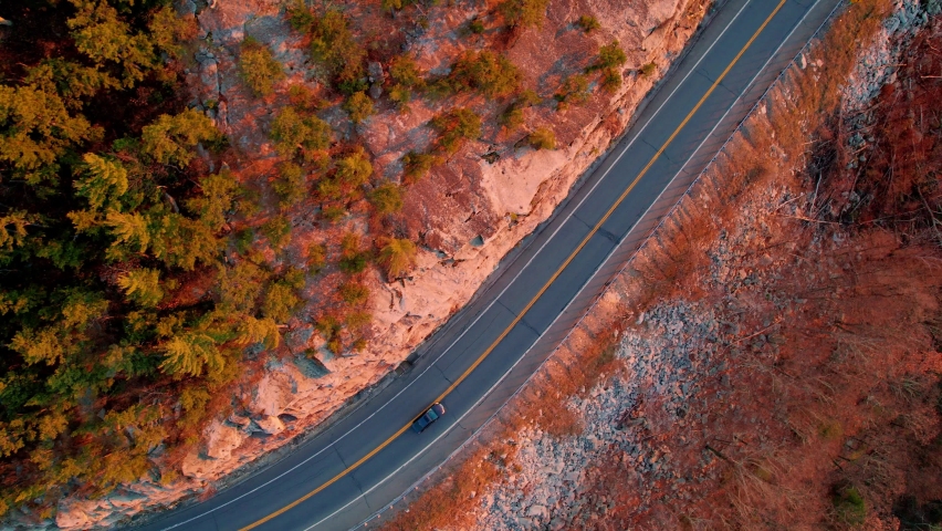 Aerial drone top down video footage of a beautiful mountain highway during fall autumn in the Appalachian Mountains, with golden light at sunset. This is in the Shawangunk Mountains in particular