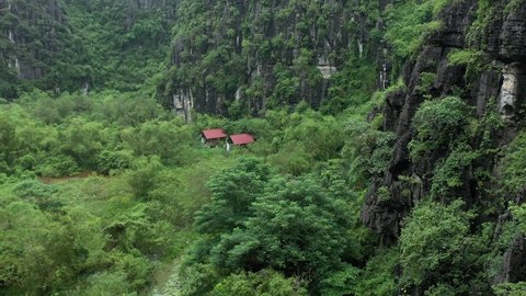 aerial drone shot of two houses hidden in the forest in Ninh Binh National park. Vietnam. Lots of trees, bushes, grass, eco friendly place, environmental paradise. 