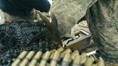 The military takes out ammunition for a large-caliber machine gun from the box and inserts it into the belts. A mountain of bullets and machine gun belts.