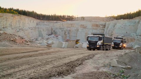 Industrial machinery deals with the granite transportation process. Industrial trucks are transporting the granite rocks from the quarry. Industrial transportation trucks are carrying the granite.
