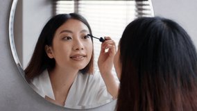 Makeup Concept. Young Beautiful Asian Female Applying Mascara On Eyelashes While Standing Near Mirror In Bathroom, Smiling Woman Looking At Reflection And Enjoying Her Natural Look, Slow Motion - Powered by Shutterstock - Get 15% off with code: PIKWIZARD15