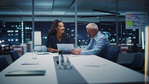Businesspeople in Modern Office: Business Meeting of Two Managers. Female CEO and Marketing Director Talk, Brainstorm Corporate Strategy, Implementing Marketing and Financial Plans. Evening Time.