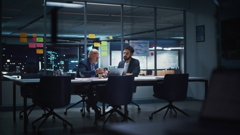 Businesspeople in Modern Office: Business Meeting of Two Managers. CEO and Operations Director Talk, Discuss, Brainstorm Corporate Strategy, Implementing Marketing and Financial Plans. Evening Time.
