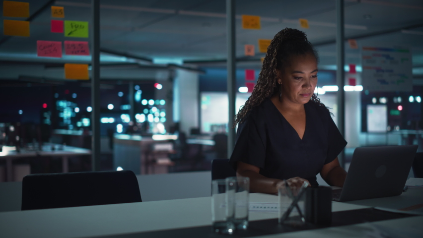 Overworked African American Businesswoman Working on Laptop Computer in Big City Office Late in the Evening. Tired Stressed Female Entrepreneur trying to Find Solution for Business Problems. Royalty-Free Stock Footage #1083680494