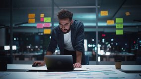 Successful Handsome Art Director Working on Laptop Computer in Big City Office Late in the Evening. Businessman Preparing for a Marketing Plan Meeting Discussion with Board Members in Conference Room. - Powered by Shutterstock - Get 15% off with code: PIKWIZARD15