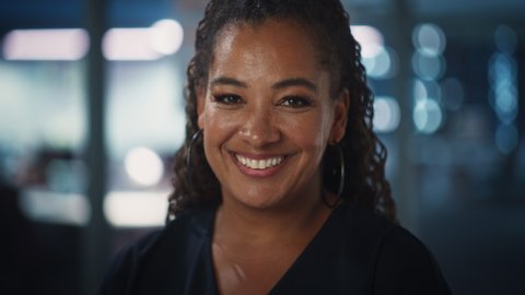 Portrait of a Confident Happy Adult Middle Aged African American Female Wearing Dark Dress, Looking at Camera, Posing and Charmingly Smiling. Successful Black Woman Working in Diverse Company Office.