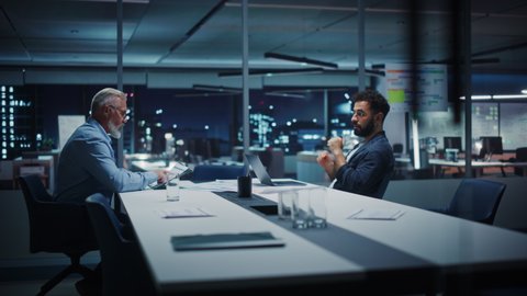 Businesspeople in Modern Office: Business Meeting of Two Managers. CEO and Operations Director Talk, Discuss Corporate Strategy, Implementing Marketing and Financial Plans. Evening Time.