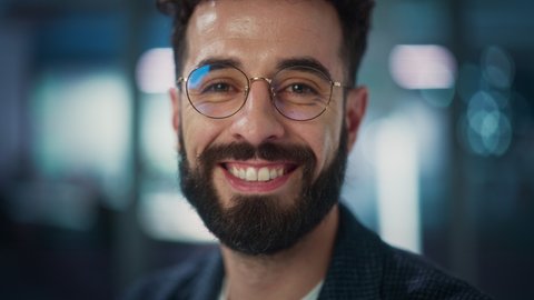 Portrait of Handsome Man with Deep Brown Eyes, Wearing Stylish Glasses. Shows Warm, Kind, Charming Smile. Attractive Modern Gentleman Looks at the Camera. Close-up Bokeh Background